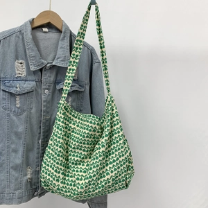 Detail of green heart tulip canvas tote bag hanging next to a denim jacket