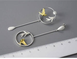 Macro detail of S925 silver bird and willow leaf earrings with measuring scale