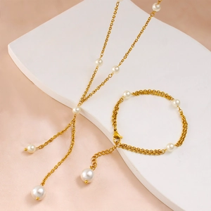 Detail of gold pearl necklace and layered bracelet set on geometric stands
