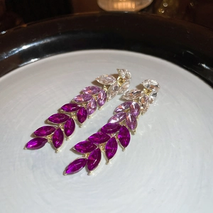 Macro view of crystal leaf tassel earrings with purple marquise stones in gold finish