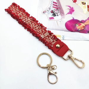 Detail of red and white tweed wristlet strap with gold metal clasp and woven texture