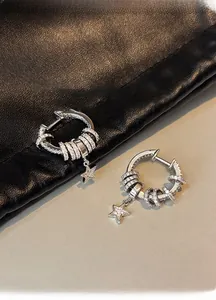 Detailed close-up of silver earrings with zircon pavé stars on a leather backdrop