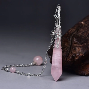 Detail of rose quartz hexagonal pendant with silver floral cap on a rustic wood background