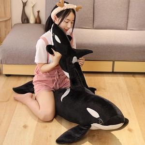 Two sizes of black and white plush orca toys displayed in a cozy home setting on wood floors