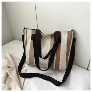 Detail of striped canvas tote bag with brown fabric strap and large capacity texture