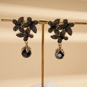 Detail of gothic floral earrings with black crystals and teardrop beads on a gold stand