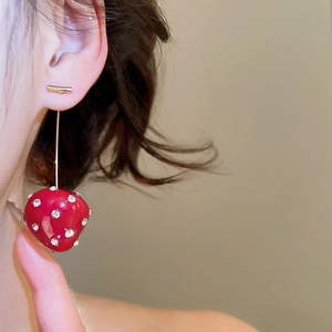 Detailed close-up of a red resin strawberry earring with sparkling rhinestones and gold stem