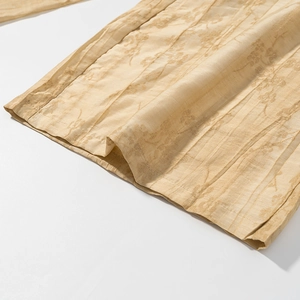 Detailed view of the jacquard floral embroidery on beige shirt cuffs and hem fabric texture