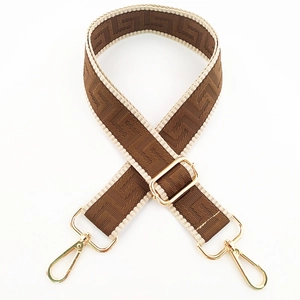 Macro detail of brown geometric fabric bag strap with golden metal swivel hooks