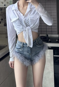 Detailansicht der Denim-Shorts mit grauem Federbesatz und weißen Schnürärmeln am Hemd