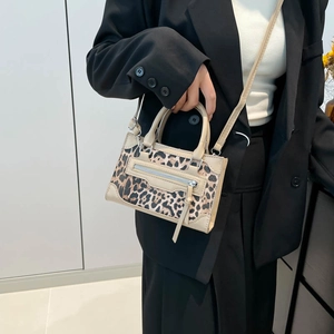 Chic leopard print crossbody bag with beige cylindrical handles and adjustable strap