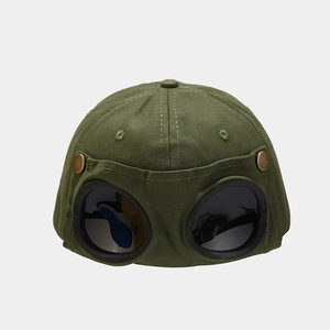 Detail of army green goggle baseball cap showing fixed black lenses and metal buttons