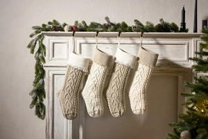 Knitted Christmas stockings with heart tassel hanging from a white vintage fireplace