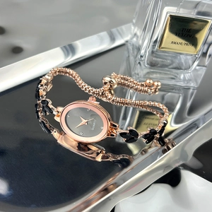 Detail view of oval rose gold quartz watch with black leaf gemstones and draw buckle
