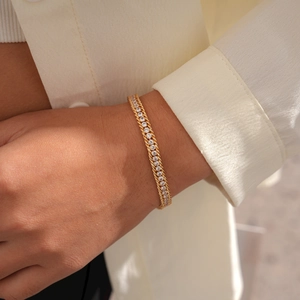 Detail of gold-plated woven chain bracelet featuring sparkling cubic zirconia stones