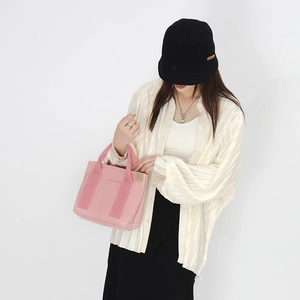 Pink canvas handbag with front pocket detail held by model in casual lifestyle setting