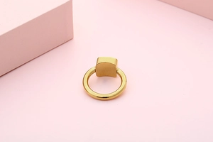 Detail view of a polished gold titanium steel ring with a modern square top design