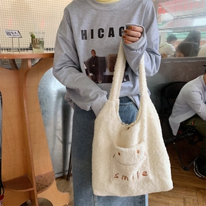 Detail der weißen Plüschtasche mit Smile-Stickerei in einer Lifestyle-Umgebung