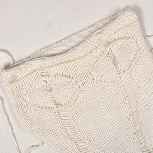 Detaillierte Nahaufnahme von cremefarbenem Strickstoff mit feinem Lochmuster und Textur