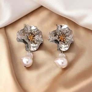 Detailed view of silver flower earrings featuring golden stamens and baroque pearls