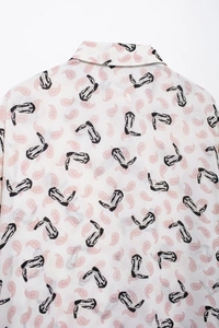 Detail of vintage paisley and cowboy boot print on white long-sleeve blouse fabric