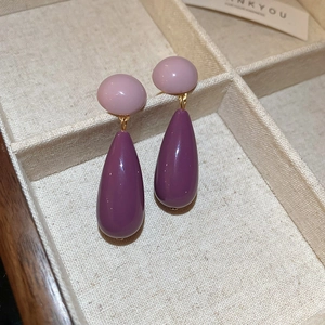 Detail view of retro purple acrylic teardrop earrings displayed in a wooden jewelry box