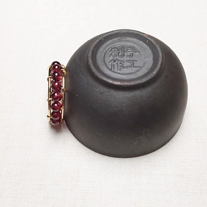 Detail of handcrafted wire-wrapped garnet ring with 14K gold filled weaving design