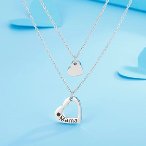 Vue macro d'un collier argenté double rang avec pendentif coeur gravé du mot Mama