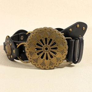 Détail d'une ceinture vintage noire avec boucle fleur en bronze et clous métalliques