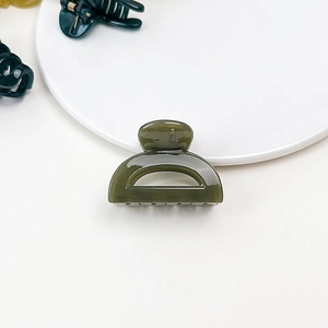Detail shot of a dark green jelly-textured small hair claw clip in a glossy finish