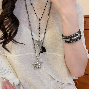 Détail du collier à cordons multicouches avec pendentifs cœur, étoile et pompons noirs