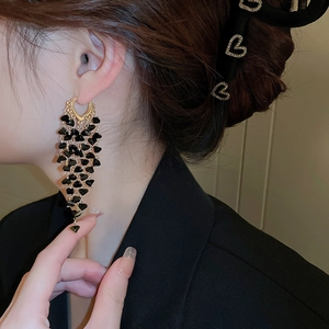 Gothic gold tassel earrings with black crystal hearts on an elegant female model
