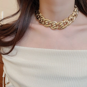 Fashionable model wearing a chunky gold chain necklace with a bold luxury metal aesthetic