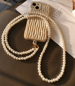 Detail of beaded pearl phone lanyard with gold clasp and wavy texture phone case