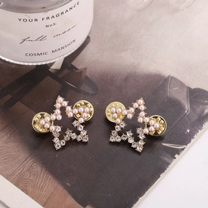 Macro detail of star-shaped earrings with pearls, crystals, and gold-plated finish