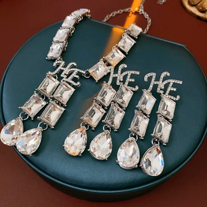Macro detail of silver-tone jewelry set with crystal drops on a green velvet box