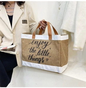 Detail of the linen tote bag featuring enjoy the little things print and leather handles