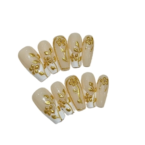 Handmade coffin nails with nude and white base featuring gold 3D floral embossed design