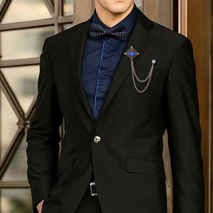Detail of vintage bronze brooch with blue gem and layered chains on black suit lapel