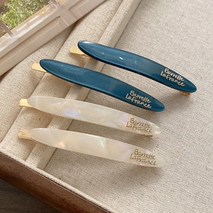 Detailed view of elegant blue and pearl white resin barrettes on a fabric display tray