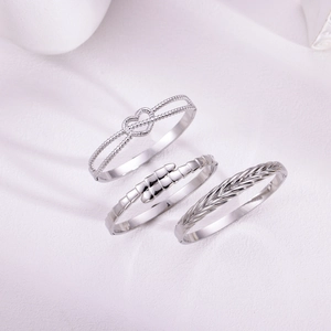 Three-piece silver cuff bracelet set featuring heart charms and woven textures