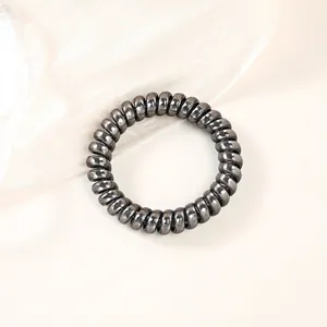 Detail shot of spiral telephone cord hair tie with metallic grey finish on silk fabric