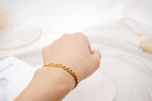 Close-up of gold asymmetrical layered chain bracelet with beads on a model wrist