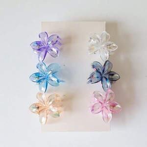 Set of six colorful flower-shaped hair claws with holographic finish on aesthetic background