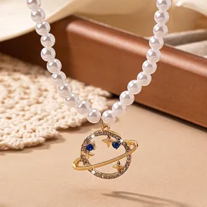 Irregular pearl necklace with golden Saturn planet pendant and sparkling blue gemstones