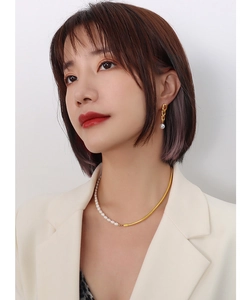 Close-up of pearl and gold chain necklace with matching twisted gold pearl earrings on model