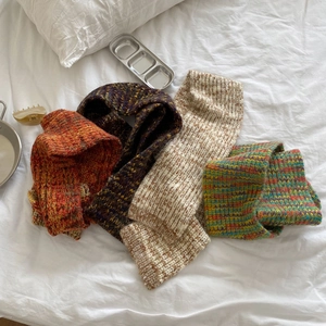 Flat lay of four colorful knit scarves in retro patterns on a soft white bedsheet