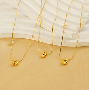 Detail of chubby golden 26 letter pendants with zircon stone on stainless steel necklace