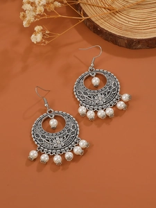 Detail of vintage bohemian silver hollow engraved earrings with white beads and tassels