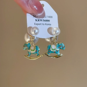 Detailed close-up of green enamel rocking horse earrings with pearls and 925 silver needles